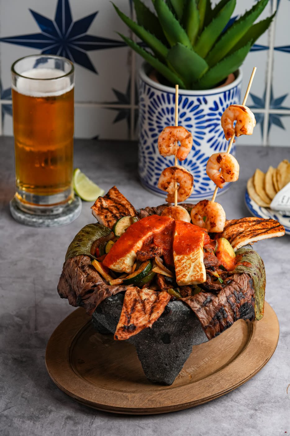 Molcajete mixto — carne asada, pollo al pastor, camarón and panela in a volcanic-stone bowl